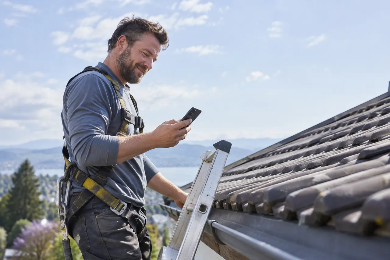 Roofing contractor on a ladder checking his phone after a call was answered while he was on the job