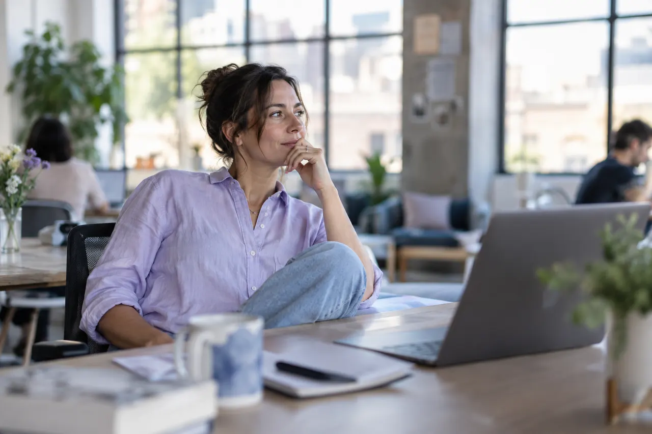 Agency founder leaning back from a laptop weighing a decision